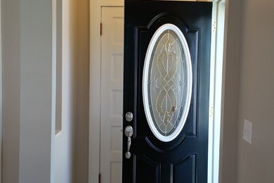 Photo of a modern entryway in Minneapolis with light hardwood floors and a black front door.