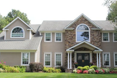 Inspiration for a mid-sized two-storey beige house exterior in New York with vinyl siding and a shingle roof.