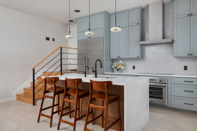 Example of a mid-sized transitional galley porcelain tile and beige floor kitchen design in Austin with an undermount sink, shaker cabinets, gray cabinets, quartz countertops, white backsplash, ceramic backsplash, stainless steel appliances, an island and white countertops