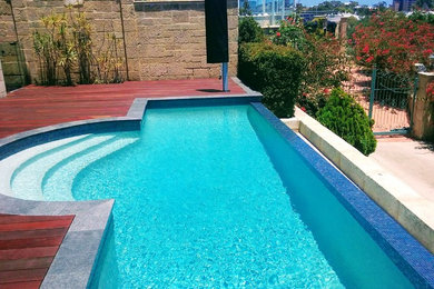 This is an example of a mid-sized modern backyard custom-shaped infinity pool in Perth with decking.