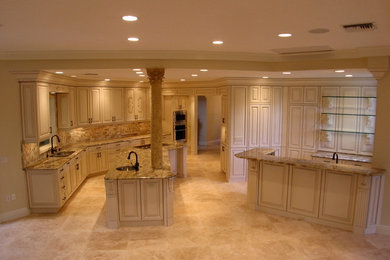 Inspiration for a large mediterranean marble floor open concept kitchen remodel in Tampa with an undermount sink, recessed-panel cabinets, beige cabinets, granite countertops, beige backsplash, paneled appliances and an island