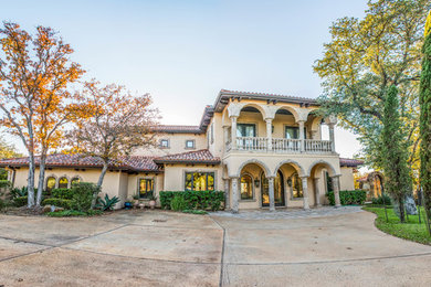 Tuscan beige two-story stucco exterior home photo in Austin with a tile roof