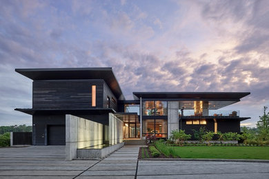 This is an example of a large modern two-storey black house exterior in Other with a flat roof and mixed siding.