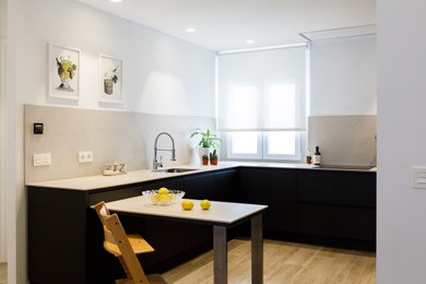 Photo of a contemporary grey and white u-shaped open plan kitchen in Madrid with a submerged sink, flat-panel cabinets, grey cabinets, limestone worktops, beige splashback, limestone splashback, stainless steel appliances, porcelain flooring, a breakfast bar, beige floors and beige worktops.