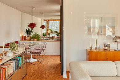 This is an example of a midcentury dining room in Berlin with white walls, orange floors and cork flooring.