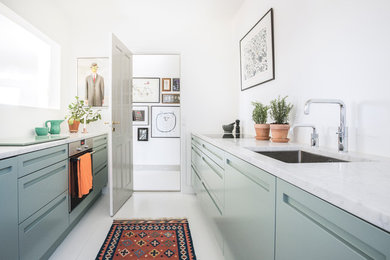 Photo of a mid-sized scandinavian galley separate kitchen in Copenhagen with a drop-in sink, flat-panel cabinets, green cabinets, marble benchtops, stainless steel appliances, laminate floors and no island.