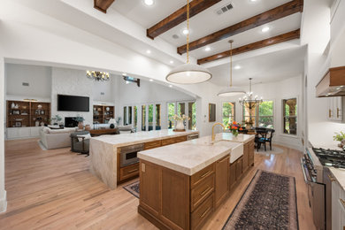 Example of a minimalist medium tone wood floor, brown floor and vaulted ceiling kitchen design in Dallas with an undermount sink, shaker cabinets, medium tone wood cabinets, quartzite countertops, stainless steel appliances, two islands and beige countertops