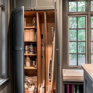 Ejemplo de lavadero multiusos, nórdico, grande, con puertas de armario grises, encimera de cuarzo compacto, paredes grises, suelo de madera en tonos medios, lavadora y secadora juntas y armarios con paneles empotrados