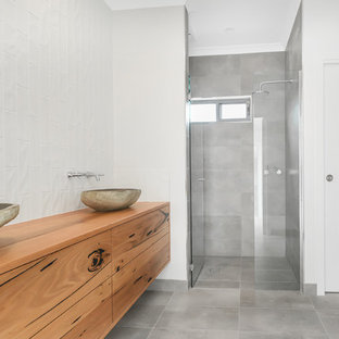 Immagine di una stanza da bagno con doccia moderna di medie dimensioni con ante lisce, ante in legno scuro, doccia doppia, piastrelle bianche, piastrelle in gres porcellanato, pareti gialle, lavabo a bacinella, top piastrellato, pavimento grigio, porta doccia a battente e pavimento in gres porcellanato