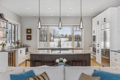 Inspiration for a large contemporary light wood floor and yellow floor open concept kitchen remodel in Calgary with shaker cabinets, white cabinets, quartzite countertops, stainless steel appliances, two islands, a farmhouse sink, multicolored backsplash and multicolored countertops