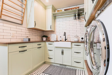 Idéer för en bruna tvättstuga, med gröna skåp, träbänkskiva, vitt stänkskydd, stänkskydd i keramik och en tvättmaskin och torktumlare bredvid varandra