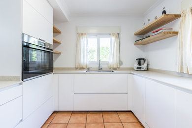 Imagen de cocina blanca y madera minimalista grande con fregadero bajoencimera y península