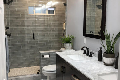 Mid-sized mid-century modern 3/4 green tile and subway tile porcelain tile, white floor and double-sink bathroom photo in New York with shaker cabinets, black cabinets, a two-piece toilet, gray walls, an undermount sink, marble countertops, a hinged shower door, white countertops and a freestanding vanity