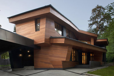 Photo of a contemporary two-storey brown house exterior in Moscow with wood siding and a flat roof.