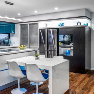 Mid-sized contemporary l-shaped kitchen pantry in Brisbane with an undermount sink, flat-panel cabinets, turquoise cabinets, quartz benchtops, black appliances, medium hardwood floors and with island.