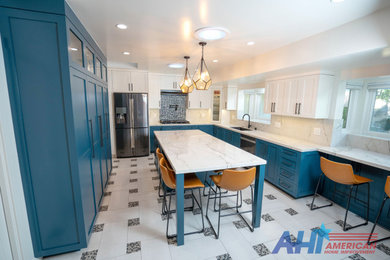 Example of a mid-sized minimalist u-shaped porcelain tile, multicolored floor and tray ceiling open concept kitchen design in Los Angeles with a drop-in sink, raised-panel cabinets, blue cabinets, marble countertops, white backsplash, marble backsplash, stainless steel appliances, an island and white countertops