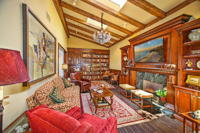 Family room library - traditional dark wood floor family room library idea in Orange County with yellow walls, a standard fireplace, a wood fireplace surround and a concealed tv