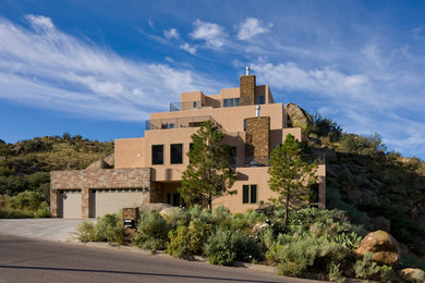 Large southwestern beige three-story stucco exterior home idea in Albuquerque