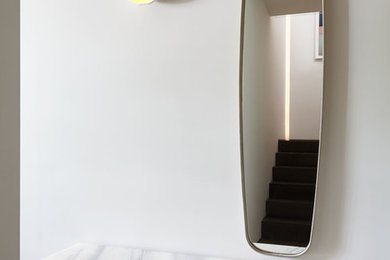 Entryway - small modern medium tone wood floor and brown floor entryway idea in New York with white walls and a white front door