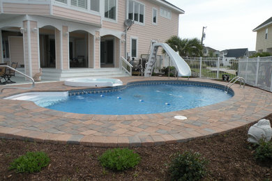 Inspiration for a mid-sized backyard brick and kidney-shaped hot tub remodel in Other