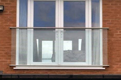 Ejemplo de balcones minimalista pequeño en anexo de casas con barandilla de vidrio