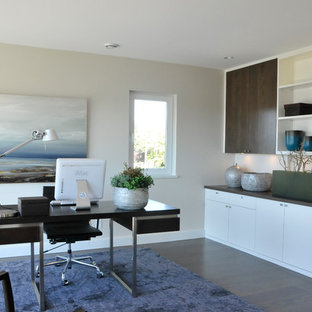 Large modern home studio in Vancouver with beige walls, dark hardwood flooring, a freestanding desk, brown floors, a two-sided fireplace and a stone fireplace surround.