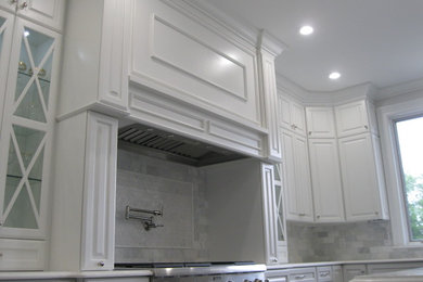 Large u-shaped dark wood floor and brown floor eat-in kitchen photo in Other with an undermount sink, raised-panel cabinets, white cabinets, quartz countertops, white backsplash, marble backsplash, stainless steel appliances and an island