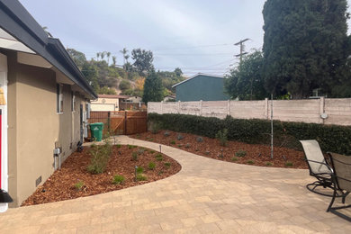This is an example of a craftsman drought-tolerant and full sun concrete paver and wood fence walkway in San Diego for summer.
