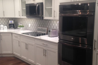 Inspiration for a transitional kitchen remodel in Other with flat-panel cabinets, white cabinets, quartz countertops, gray backsplash, ceramic backsplash and an island