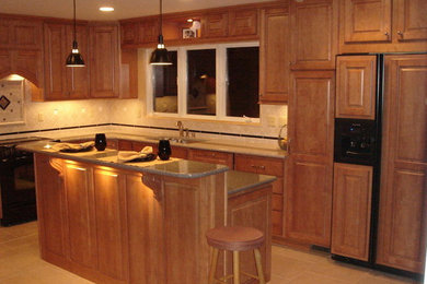 Photo of a mid-sized traditional l-shaped eat-in kitchen in Detroit with raised-panel cabinets, medium wood cabinets, granite benchtops, beige splashback, panelled appliances, ceramic floors and with island.