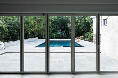 Basement - mid-sized contemporary walk-out ceramic tile and brown floor basement idea in New York with white walls