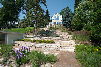 This is an example of a mid-sized traditional backyard full sun garden for summer in Milwaukee with a water feature and natural stone pavers.