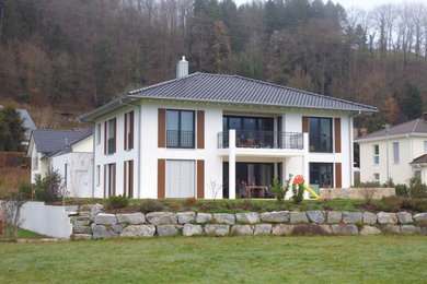 Photo of a mid-sized scandinavian two-storey stucco white exterior in Stuttgart with a hip roof.