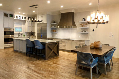 Example of a large beach style l-shaped porcelain tile and brown floor open concept kitchen design in Dallas with an undermount sink, shaker cabinets, white cabinets, granite countertops, gray backsplash, porcelain backsplash, stainless steel appliances, an island and gray countertops