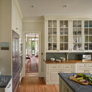 Diseño de cocina clásica con encimera de esteatita, armarios tipo vitrina, puertas de armario beige y electrodomésticos de acero inoxidable