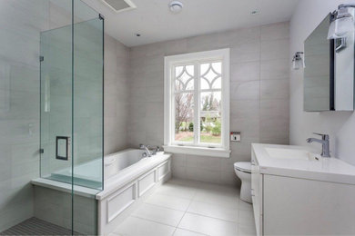 Bathroom - mid-sized transitional master gray tile and porcelain tile porcelain tile and white floor bathroom idea in Toronto with white cabinets, gray walls, an undermount sink, solid surface countertops, a hinged shower door and white countertops