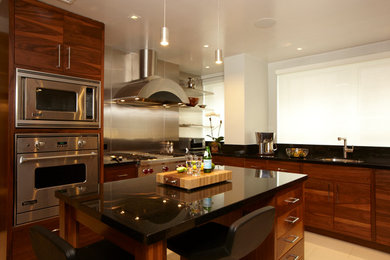 Mid-sized trendy single-wall porcelain tile eat-in kitchen photo in New York with an undermount sink, medium tone wood cabinets, granite countertops, metallic backsplash, stainless steel appliances and an island