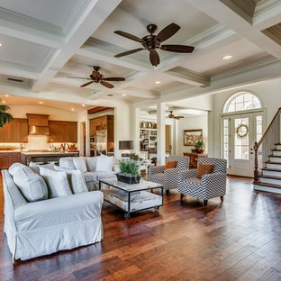 Großes, Offenes Mediterranes Wohnzimmer mit weißer Wandfarbe, braunem Holzboden, Kamin, Kaminsims aus Beton, Multimediawand und braunem Boden in Jacksonville