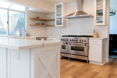 Inspiration for a large country u-shaped vinyl floor and beige floor eat-in kitchen remodel in Los Angeles with a farmhouse sink, shaker cabinets, white cabinets, quartz countertops, white backsplash, ceramic backsplash, stainless steel appliances, a peninsula and white countertops