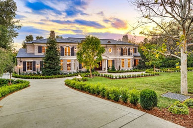 Huge traditional beige two-story stone house exterior idea in Los Angeles with a hip roof and a tile roof
