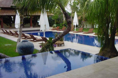 Diseño de piscinas y jacuzzis infinitos modernos extra grandes rectangulares en patio trasero con adoquines de hormigón