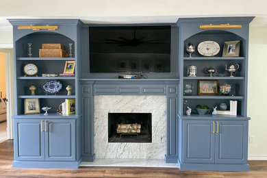 ダラスにあるお手頃価格の中くらいなトラディショナルスタイルのおしゃれなLDK (青い壁、無垢フローリング、標準型暖炉、石材の暖炉まわり、壁掛け型テレビ、茶色い床、三角天井) の写真