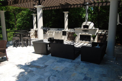 Photo of a large contemporary side yard patio in Charlotte with an outdoor kitchen, natural stone pavers and a pergola.