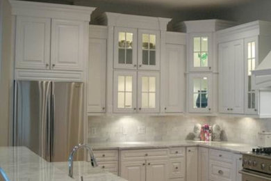 Mid-sized l-shaped medium tone wood floor open concept kitchen photo in Chicago with raised-panel cabinets, white cabinets, marble countertops, stainless steel appliances and an island