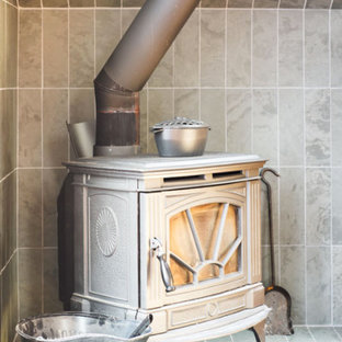 Foto på ett rustikt hemmabibliotek, med vita väggar, mellanmörkt trägolv, en öppen vedspis, en spiselkrans i sten, ett fristående skrivbord och brunt golv