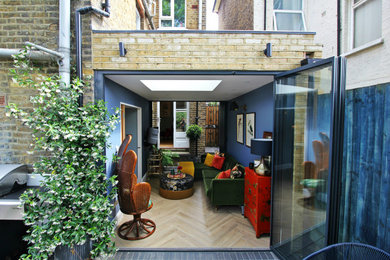 Design ideas for a small traditional enclosed living room in London with a home bar, blue walls, light hardwood flooring and a wall mounted tv.