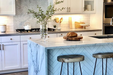 Mid-sized transitional l-shaped medium tone wood floor and brown floor open concept kitchen photo in San Diego with an undermount sink, shaker cabinets, white cabinets, marble countertops, white backsplash, subway tile backsplash, stainless steel appliances, an island and gray countertops
