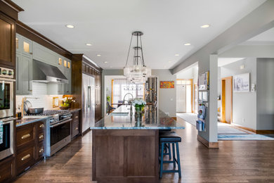 Eat-in kitchen - huge transitional single-wall medium tone wood floor and brown floor eat-in kitchen idea in Minneapolis with medium tone wood cabinets, white backsplash, ceramic backsplash, stainless steel appliances and an island