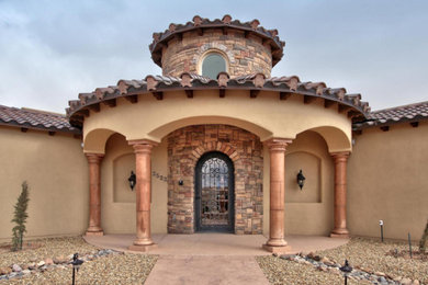 Example of a mid-sized tuscan beige one-story adobe exterior home design in Albuquerque with a hip roof