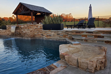 Imagen de piscina alargada exótica de tamaño medio a medida en patio trasero con paisajismo de piscina y adoquines de piedra natural